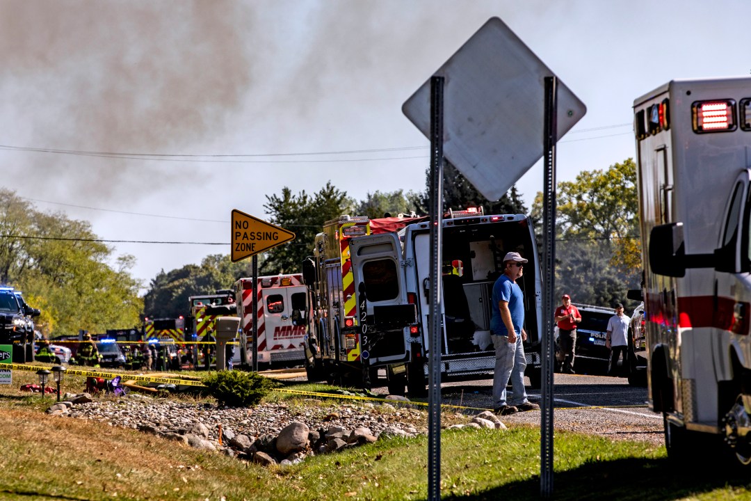 Neighbors and other community members look on as emergency services respond to a shooting and fire at a church in michigan