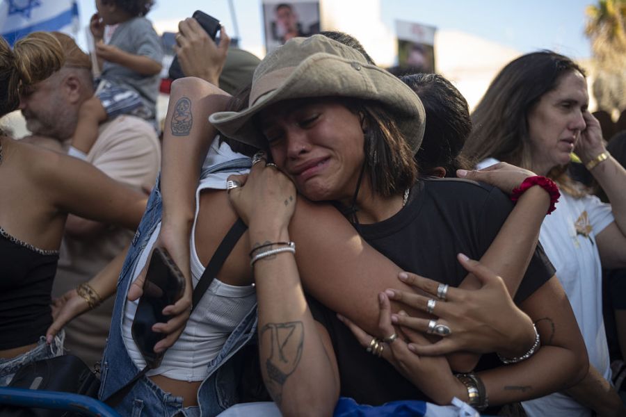 Israeli women hug in a crowd of people watching the release of hostages from hamas