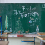 „frohe ferien“ steht an der tafel in einem klassenzimmer, in dem die stühle am letzten schultag vor den weihnachtsferien auf die tische geräumt wurden.