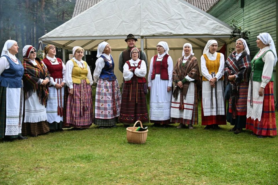 Varėnos grybavimo čempionate – 428 kilogramai grybų: alytiškiai – treti 2026 - teisingumas - iustitia. Bg Tautiniais drabužiais vilkintys šventės dalyviai žiūrų kaime