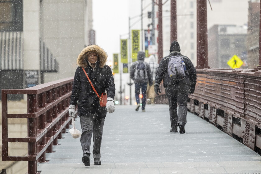 After a year of unusual weather in chicago, should you brace for winter? 2026 - justice A group of people cross the dearborn street bridge as snow falls in the chicago area.