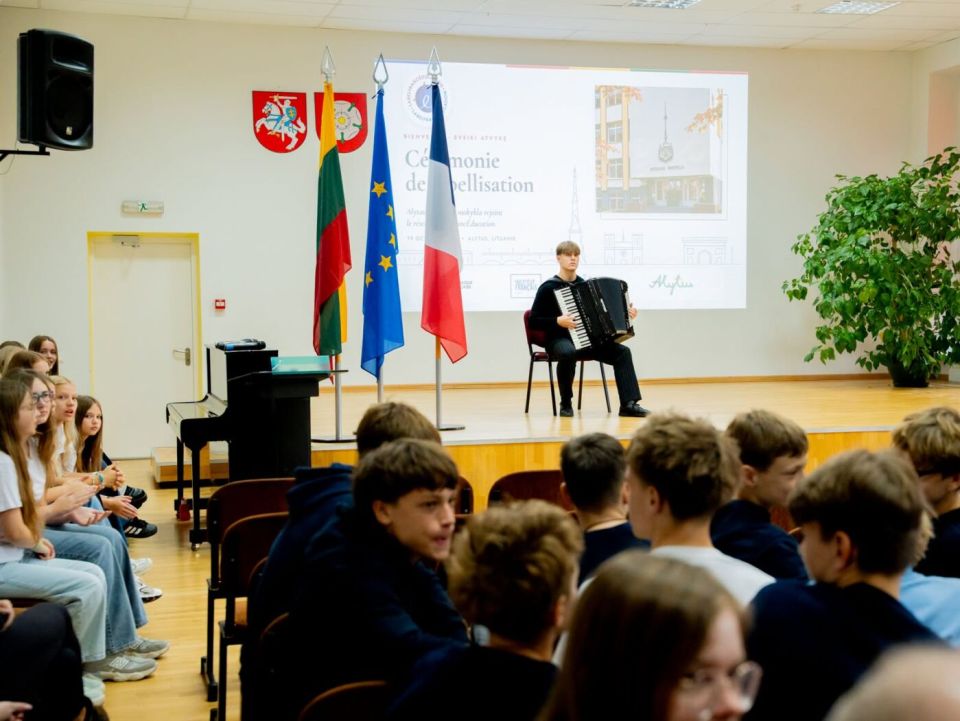 Alytaus dzūkijos mokyklai – tarptautinis „labelfrancéducation“ kokybės ženklas 2026 - teisingumas - iustitia. Bg Mokinys groja akordeonu mokyklos šventės scenoje prie lietuvos, europos sąjungos ir prancūzijos vėliavų