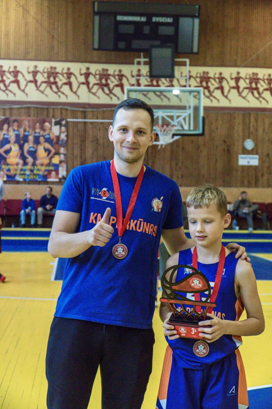 „alytus cup 2026“ finiše – jaunųjų alytiškių sidabras 2026 - teisingumas - iustitia. Bg Turnyro dalyvis ir suaugęs vyras po apdovanojimų