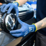 Ein mitarbeiter montiert im vw stammwerk ein vw logo in einen neuwagen volkswagen tiguan.