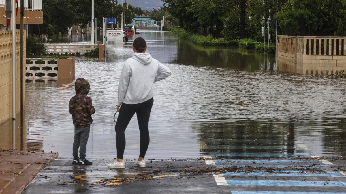 Una mujer y un niño observan una zona inundada en guardamar de la safor.