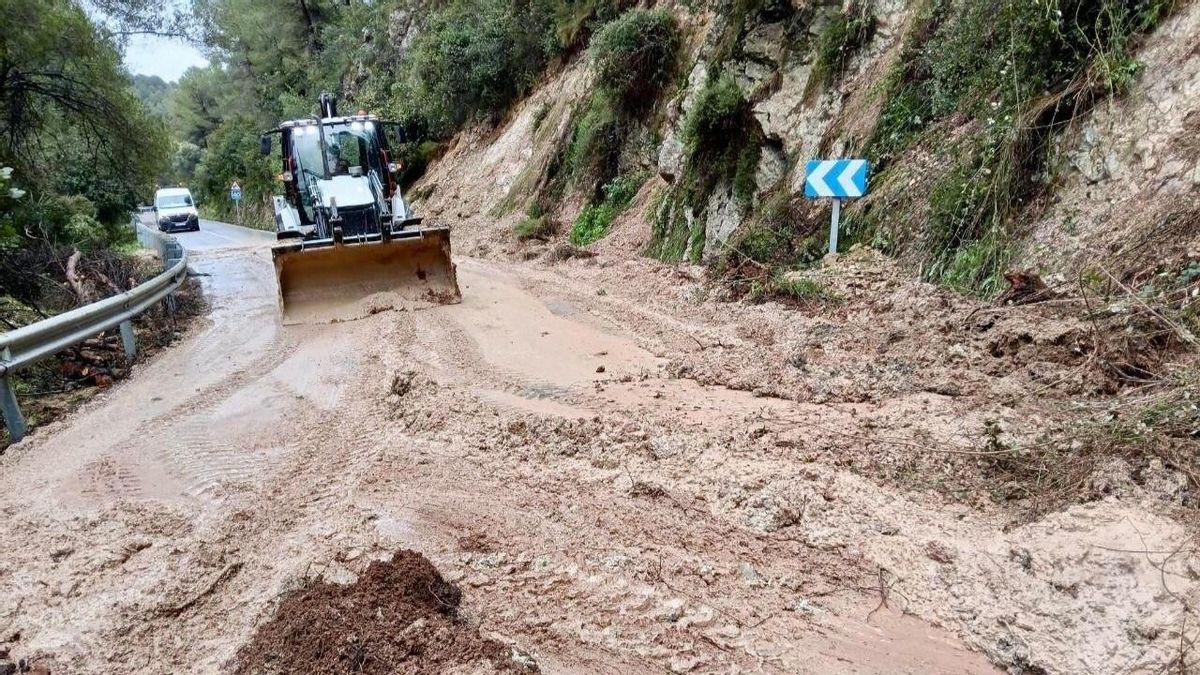Una excavadora trabaja para la apertura de una carretera afectada por la dana adam.