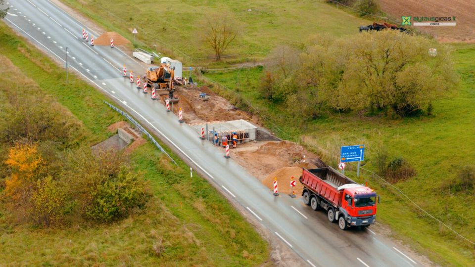 Kelionė iš alytaus į lazdijus gali užtrukti ilgiau nei valandą 2026 - teisingumas - iustitia. Bg Kelio remonto vietoje dirba ekskavatorius, darbininkai ir sunkvežimis, vaizdas iš drono.