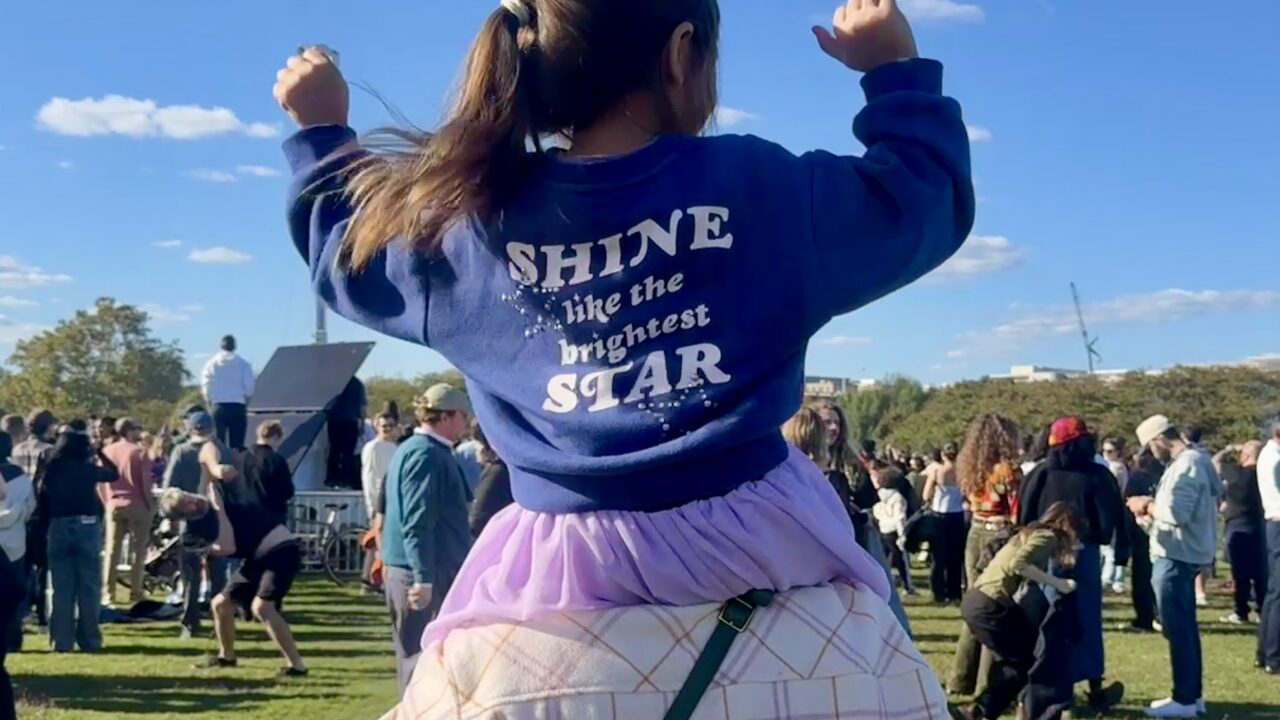 Young child sitting on top of her parent at turnstile concert