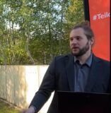 Dennis schöne (rvm) erklärt an einem großen monitor, wie die buchung der fahrten des münsterland movers über die app rufmobil. Nrw funktioniert.