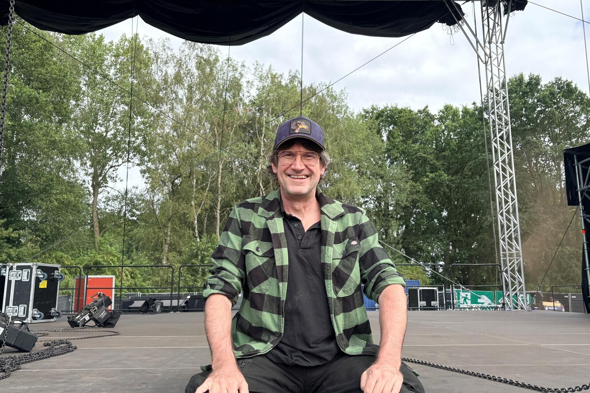 Alex schwers sitzt auf einer unfertigen bühne
