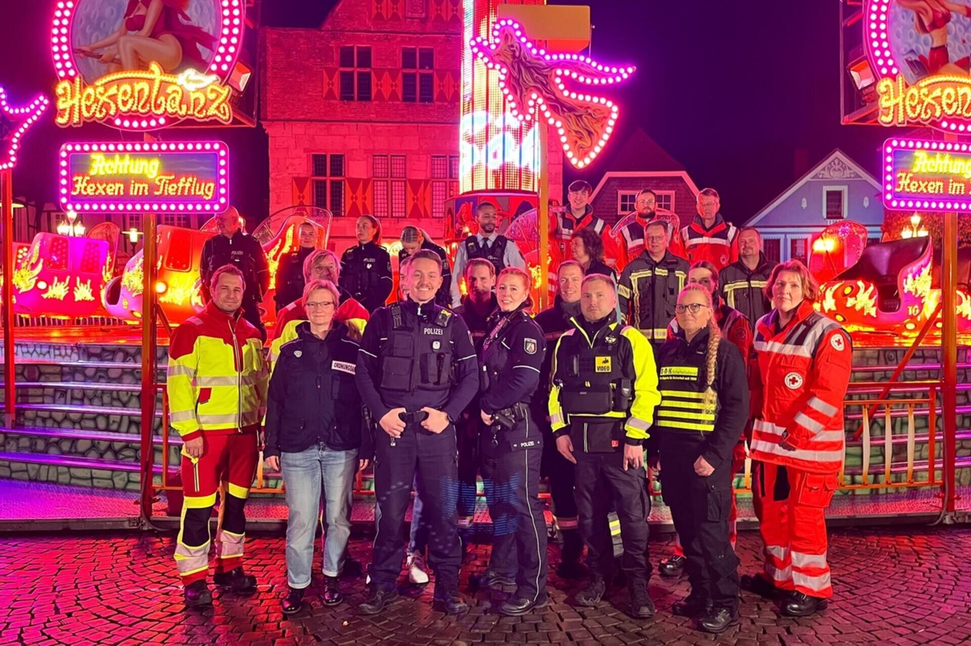 Sicherheit bei sim-jü in werne: feuerwehr leistet hunderte zusätzliche stunden 2026 - iustitia. Bg - gerechtigkeit Einsatzkräfte stehen vor einem fahrgeschäft und blicken lächelnd in die kamera.