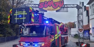 Sicherheit bei sim-jü in werne: feuerwehr leistet hunderte zusätzliche stunden 2026 - iustitia. Bg - gerechtigkeit Ein rotes feuerwehrauto mit eingeschaltetem blaulicht steht unter dem beleuchteten eingangsbogen der sim-jü in werne.
