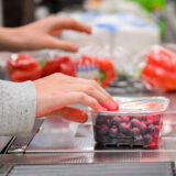 Tag der deutschen einheit: kann man am 3. Oktober in den niederlanden einkaufen? 2026 - iustitia. Bg - gerechtigkeit Aufnahme einer supermarktkasse, gerade wird ein päckchen blaubeeren über den scanner gezogen, im hintergrund liegen rote paprika, toilettenpapier und weitere artikel auf dem kassenband.