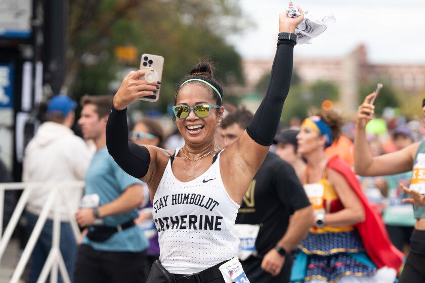 Put your name on your shirt, so the crowd along the route can give you a personal cheer, say past Chicago Marathon runners. Here, Catherine Capuli takes a video while running in Chinatown during the Bank of America Chicago Marathon in 2023.